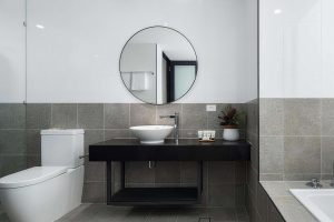 img.The image shows a modern bathroom with a shower area, a sleek vanity with a wash basin, and a mirror