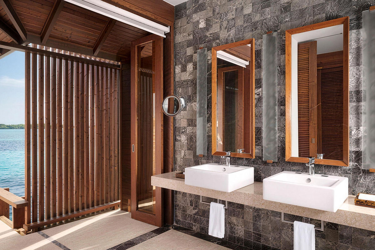 the image features a modern bathroom with two square washbasins and sleek wall-mounted faucets, highlighted by illuminated mirrors and minimalist shelving